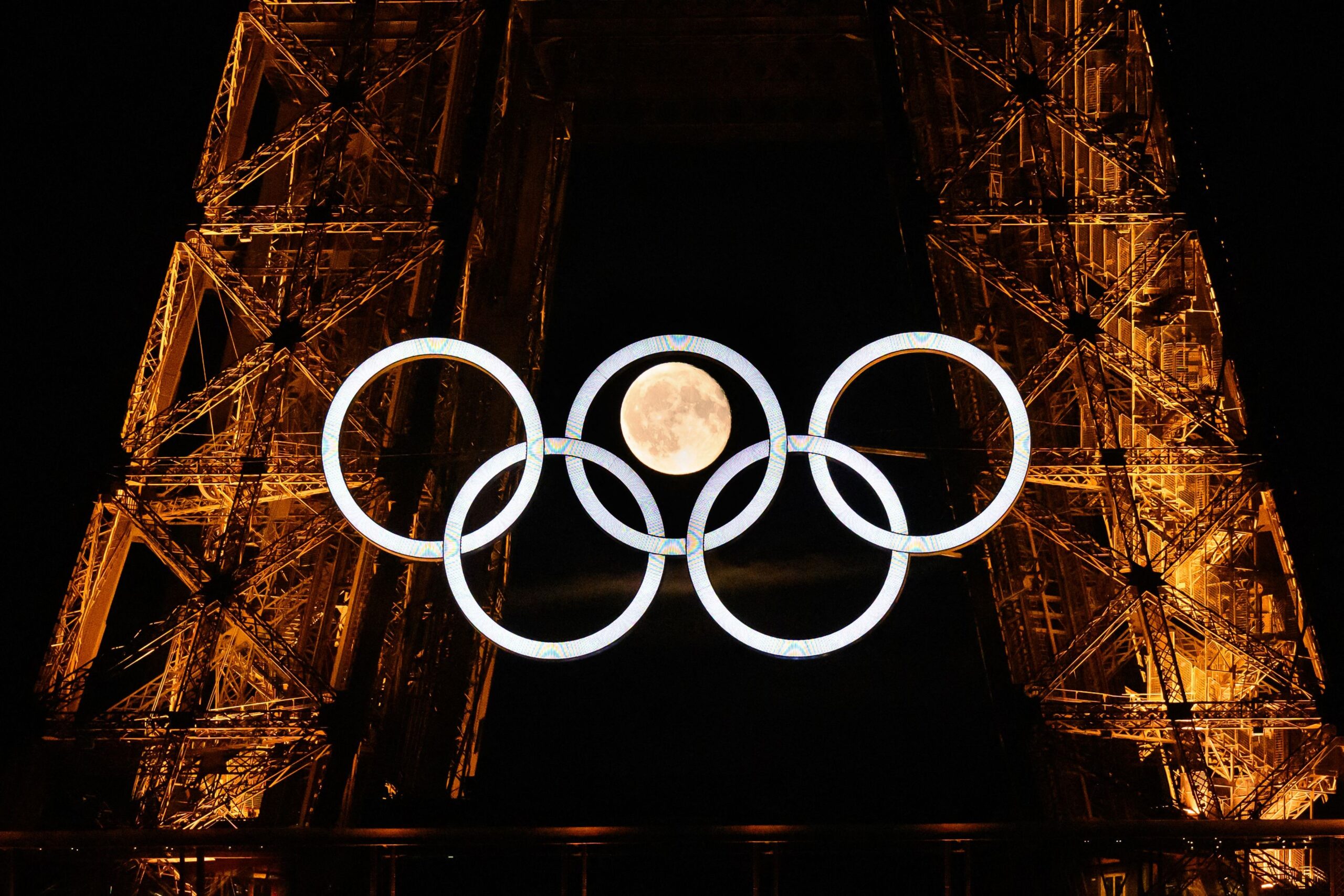 109334693-topshot-afp-pictures-of-the-year-2024-the-moon-rises-behind-the-olympic-rings-dis.jpg