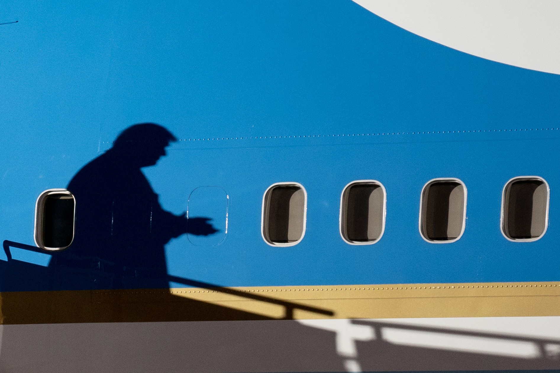 109652896-president-donald-trump-casts-a-shadow-on-air-force-one-as-he-arrives-for-a-campaign-event.jpeg