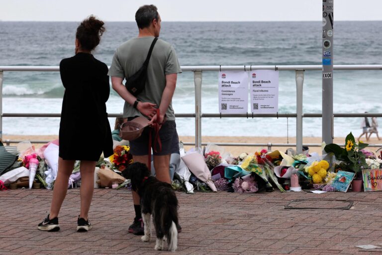 113319319-a-couple-pauses-at-floral-tributes-on-bondi-beach-to-pay-respects-to-the-victims-of-the-sy.jpeg