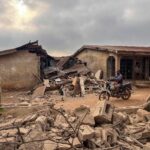 113389374-topshot-residents-and-a-motorcyclist-move-between-destroyed-structures-in-offa-on-decemb.j.jpeg