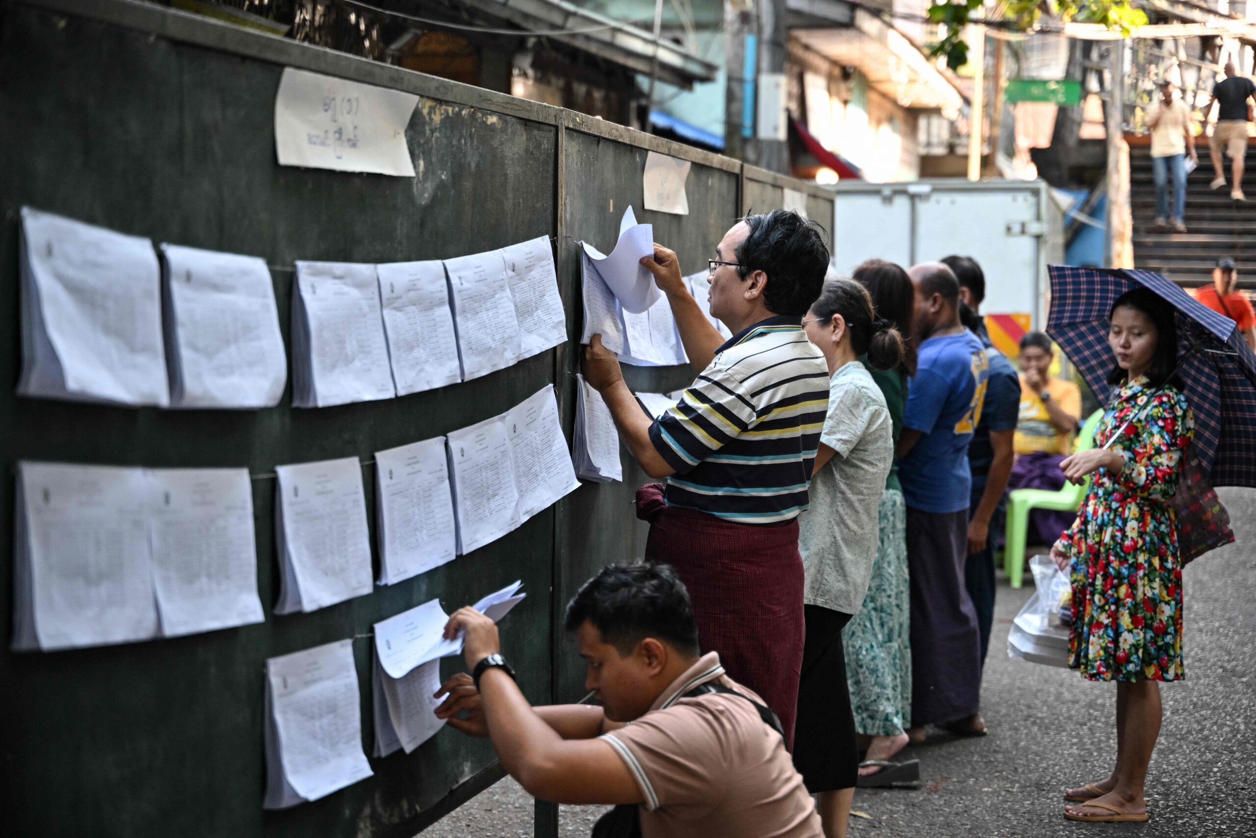 113389454-people-check-name-lists-displayed-near-a-polling-station-a-day-before-the-start-of-mya.jpg