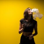 attractive-woman-standing-vaping-yellow-wall.jpg
